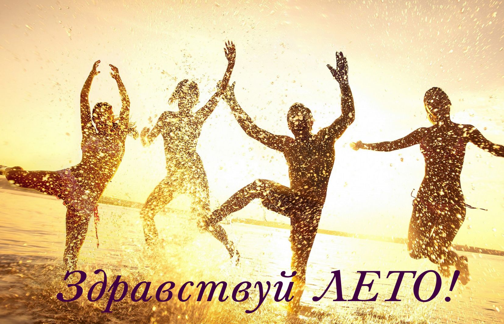 Танцующие на берегу люди в брызгах воды.