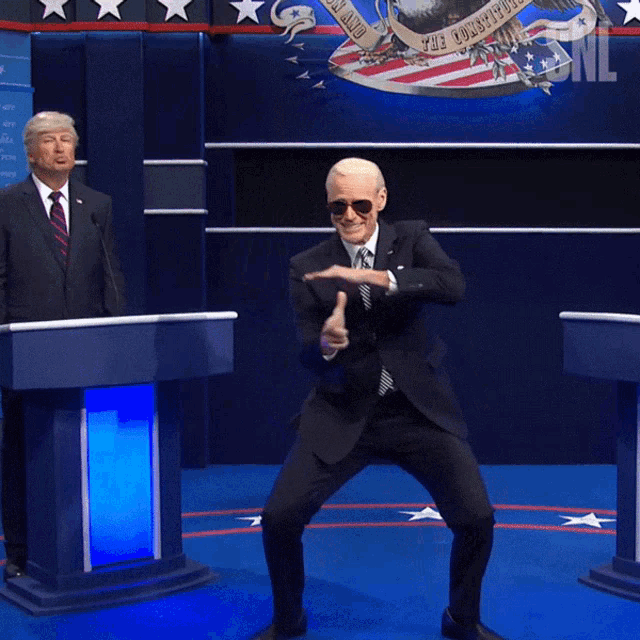 Пародия Джима Керри на Байдена, угрожающего выстрелить из невидимого автомата в невозмутимого Трампа на заднем плане