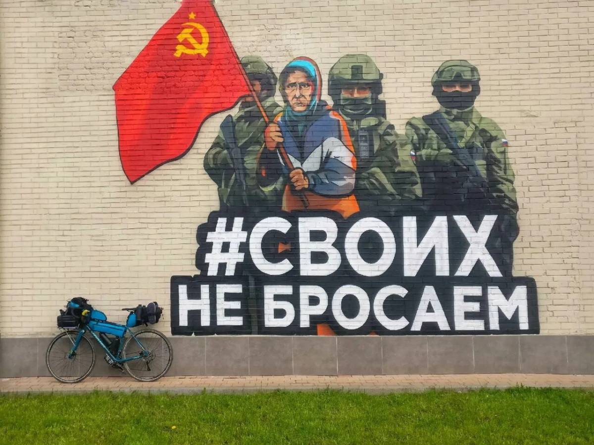 Граффити на стене Своих не бросаем бабушка с флагом СССР.