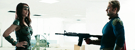 Зацикленная гифка Хоумлендер стреляет из автомата в бронированный лифчик супергеройской женщины.