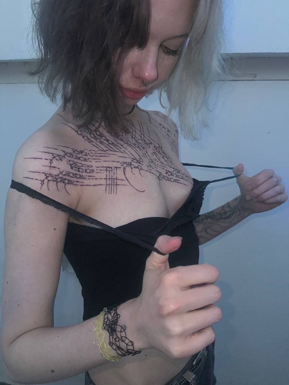 Блогерша Парадокси на фото с чёрно-белыми волосами и татуировками на груди в виде шрамов.