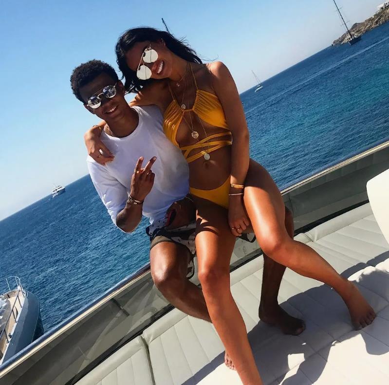 Руби Мэй в жёлтом купальнике, сидит на коленях у Деле Алли. Руби Мэй в жёлтом купальнике, сидит на коленях у Деле Алли.