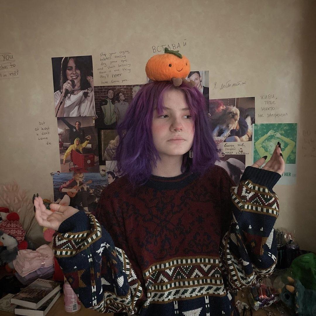 Смешное старое фото Оли "Тыквы" дома с фиолетовыми волосами и игрушечной тыквой на голове. Смешное старое фото Оли "Тыквы" дома с фиолетовыми волосами и игрушечной тыквой на голове.