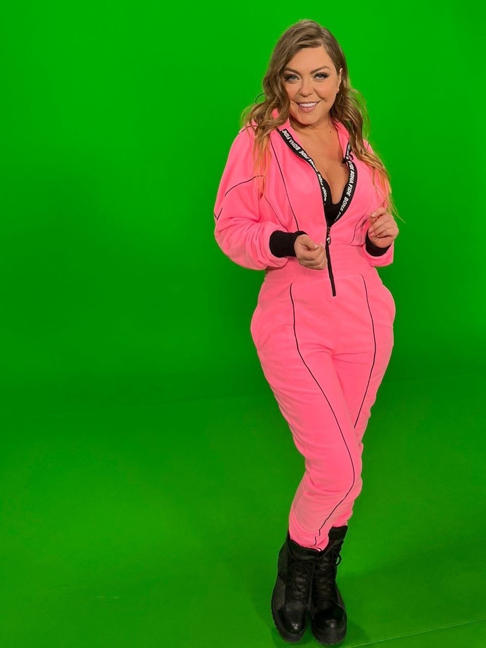 Оксана "Акула" на съёмках в спортивном костюме на зелёном фоне.