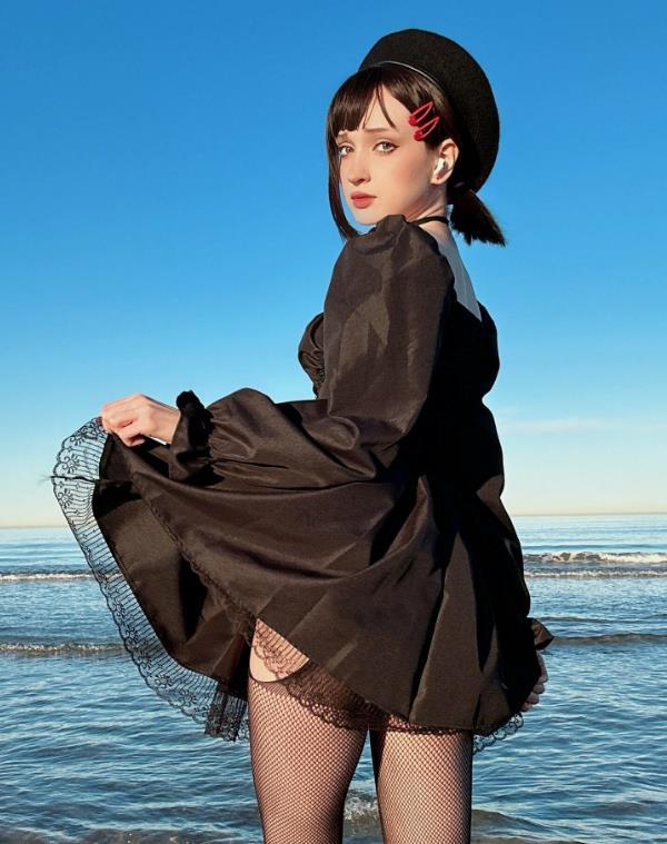 Анастасия Моначеных на фото у моря в чёрном платье и сетчатых чулках.