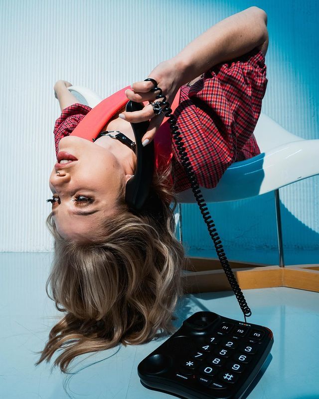 Юмористка Вяликова в верх головой с трубкой телефона и в чёрном чокере. Юмористка Вяликова в верх головой с трубкой телефона и в чёрном чокере.