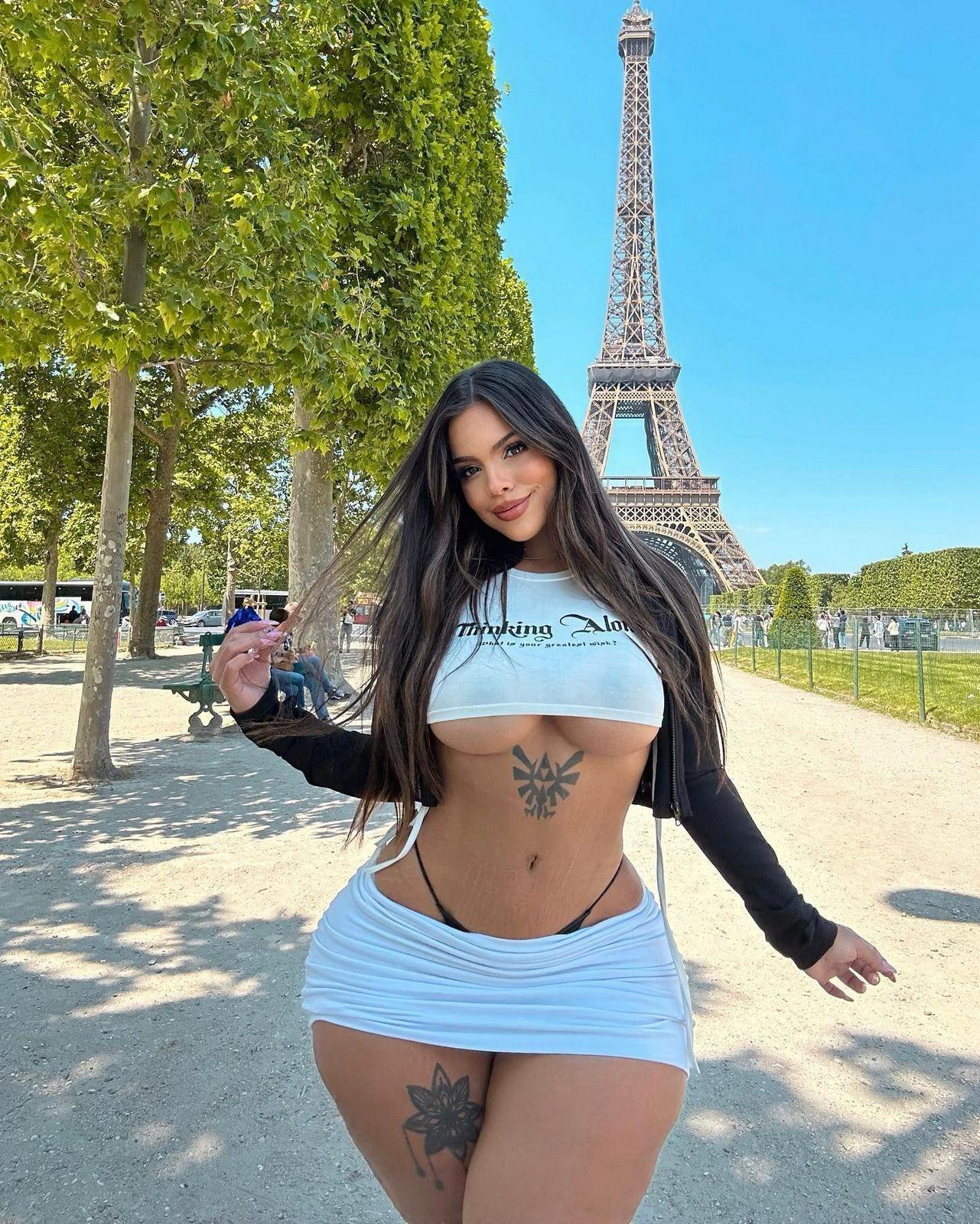 Красивый снимок Бон на фоне Эйфелевой башни в мини юбке и белой майке без лифчика.