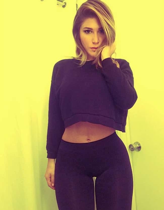 Фитоняшка Пишотта в обтягивающей спортивной одежде на жёлтом фоне. Фитоняшка Пишотта в обтягивающей спортивной одежде на жёлтом фоне.