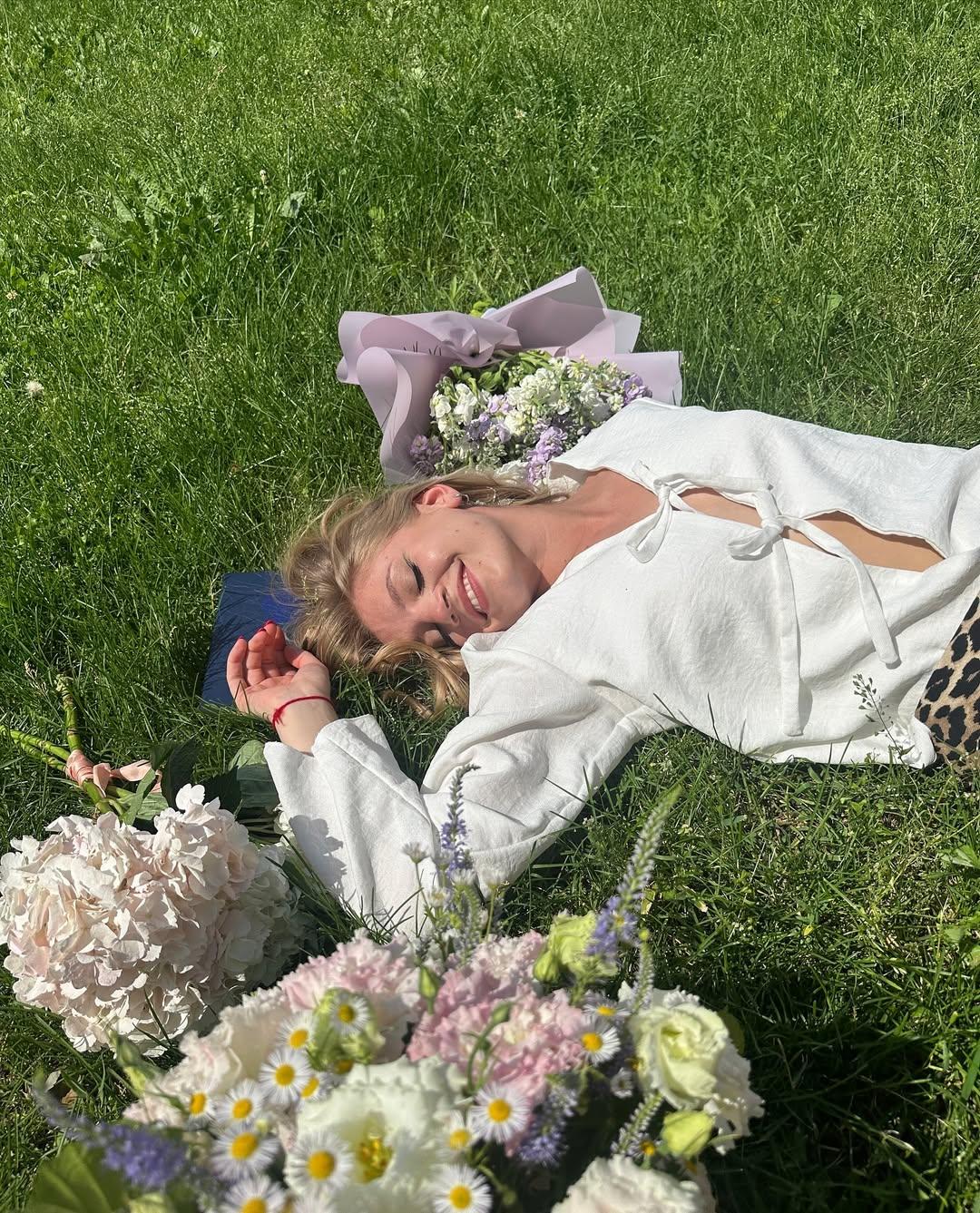 Летнее фото Карина Александрова лежит на траве в рубашке с откровенных вырезом.